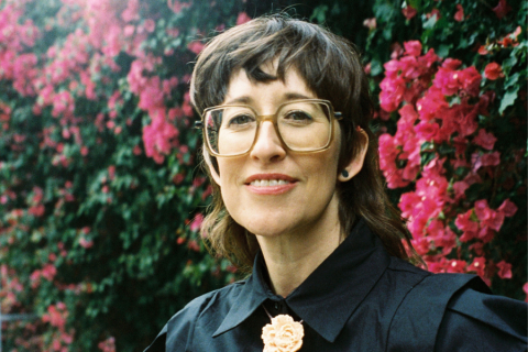 Person with glasses in front of flower wall