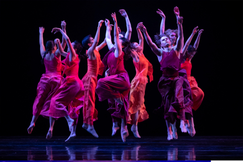 Women on stage dancing with arms in the air
