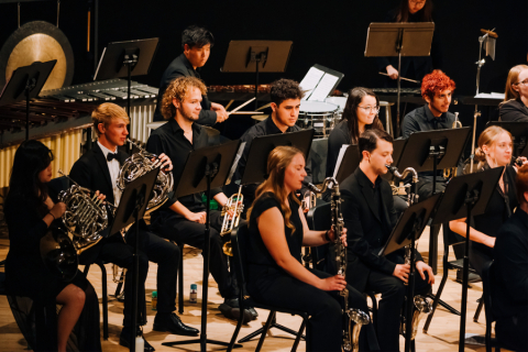 Wind ensemble seated on stage during concert